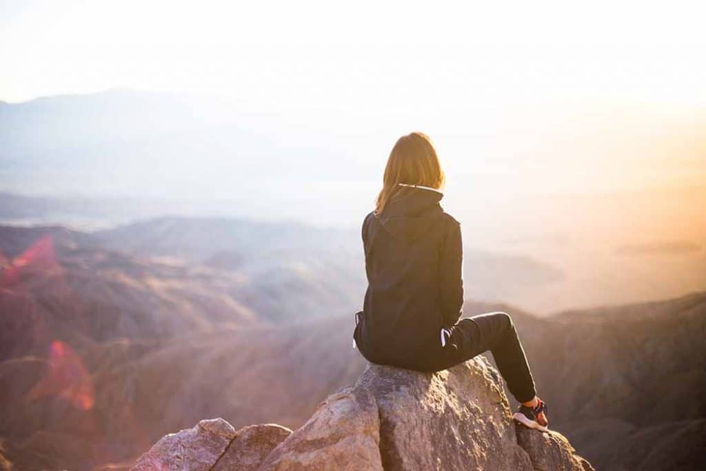 person with long hair sitting on a mountain