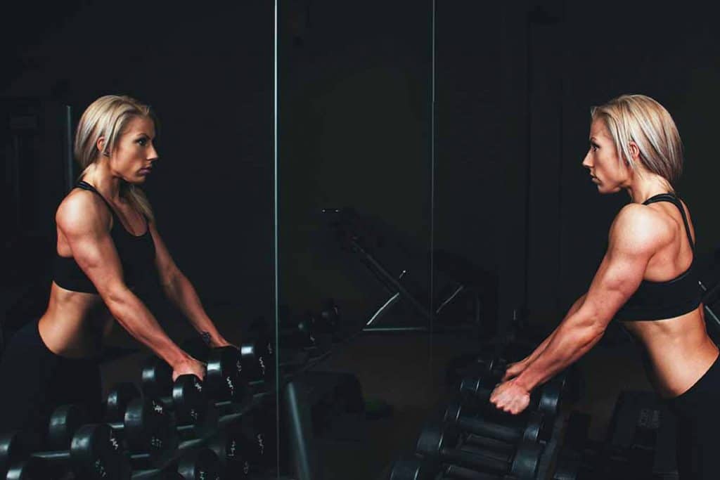 woman lifting weights off a weight rack