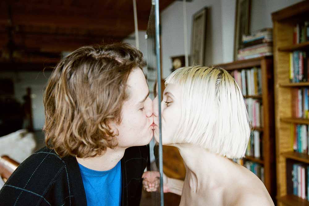 couple kissing with glass panel in the way